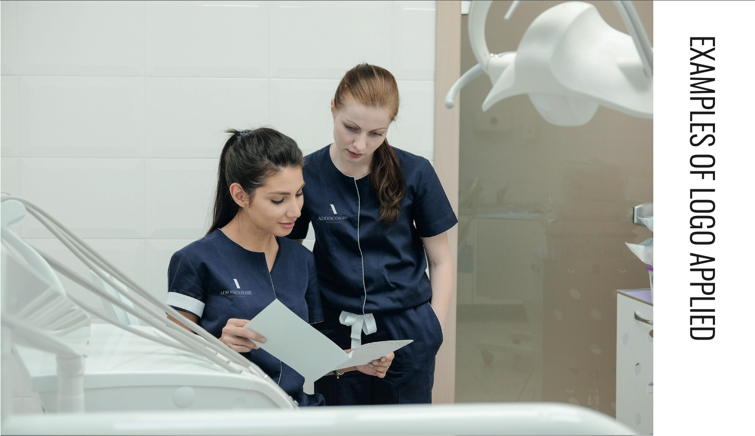 Two clinicians in navy Addiscombe-branded scrubs with the embroidered 'A ADDISCOMBE' mark, in a clean white surgery