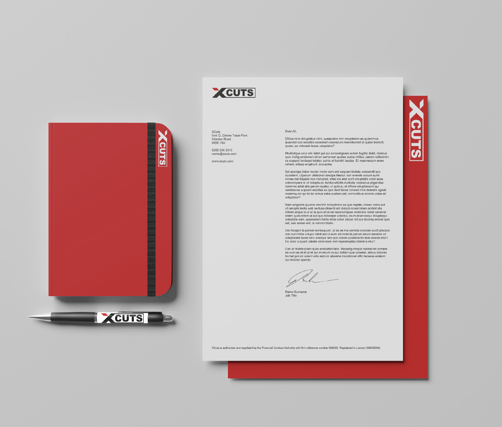 XCuts stationery suite — red notebook with black elastic band, branded pen, printed letterhead with the XCuts logo and address, and a red presentation folder